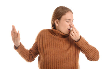 Young woman feeling bad smell on white background