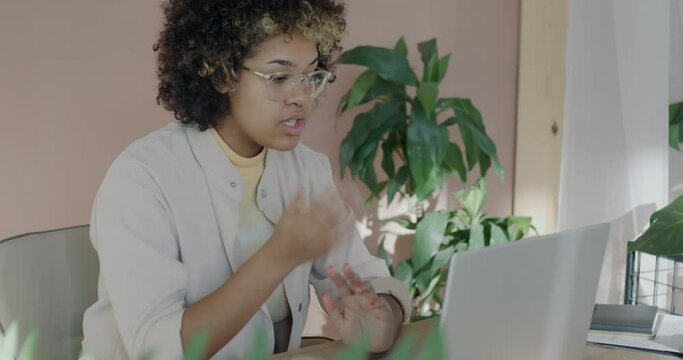 Young African American businesswoman speaking discussing start-up project during online video call with laptop in office. Virtual meeting and business development concept.