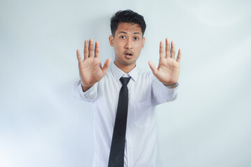 Adult Asian businessman looking camera and give stop hand sign with serious face expression