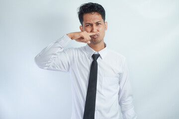 Asian businessman standing while covering his nose. Bad smell concept. Isolated on white