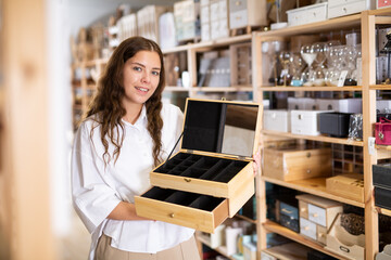 Portrait of young woman searching wooden box for jewelry storage at store