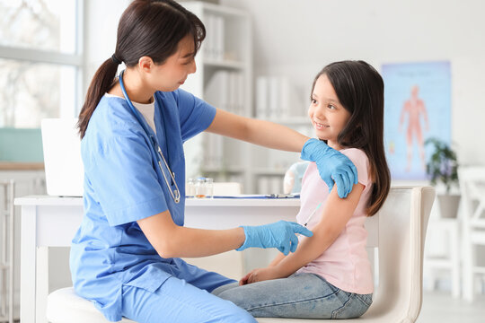 Little Asian girl receiving vaccine in clinic