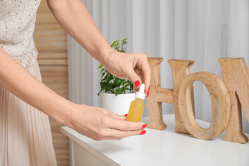 Mature woman taking bottle of CBD oil from commode at home, closeup