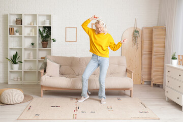 Mature woman in headphones dancing at home