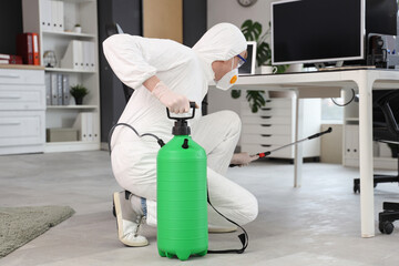 Male worker disinfecting under table in office