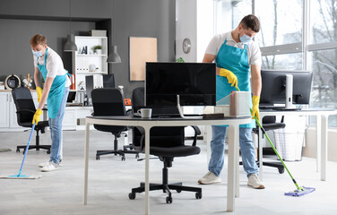 Male workers of cleaning service disinfecting in office
