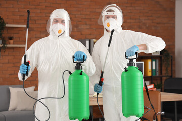 Professional workers with disinfectant in office