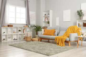 Interior of living room with grey sofa, shelf units and plants