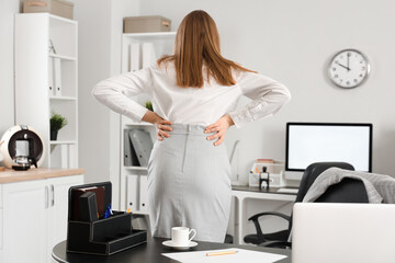 Fototapeta premium Young businesswoman suffering from back pain in office