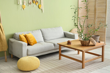 Modern interior of green living room with bamboo stems on coffee table and sofa