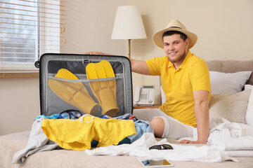 Male tourist unpacking suitcase in hotel room