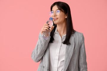 Young Asian woman drinking water on pink background