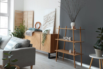 Interior of living room with drawers, shelf unit and willow branches in vase