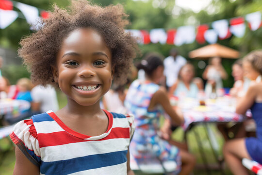 Little Afro American girl smiling wearing American t-shirt for Independence Day with barbecue celebration in the backyard