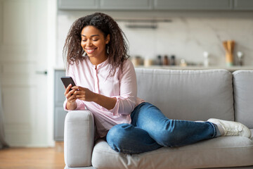 Smiling woman using smartphone on couch at home