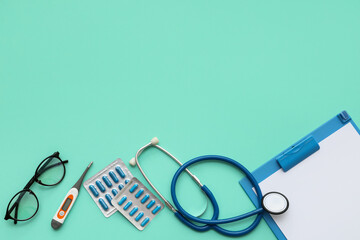 Blank clipboard with medical supplies and eyeglasses on green background. World Health Day