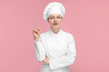 Happy chef in uniform pointing at something on pink background