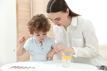 Mother and her little son painting with watercolor at home
