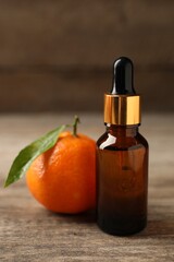 Bottle of tangerine essential oil and fresh fruit on wooden table