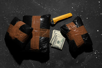 Drug packages with money and utility knife on dark background