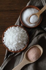 Different types of organic salt on wooden table, flat lay