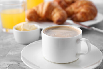 Tasty breakfast. Cup of coffee, butter and fresh croissants on grey table, closeup