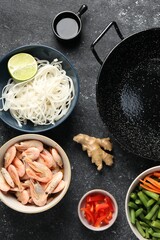 Flat lay composition with black wok and products on dark textured table