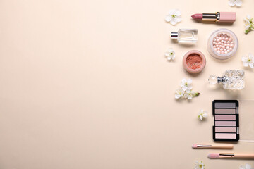 Flat lay composition with different makeup products and beautiful spring flowers on beige background, space for text