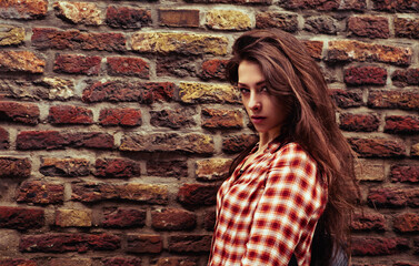 Beautiful brunette woman enjoying and standing on the old brick wall building background in casual red shirt on the spring city. Closeup vintage portrait of model. - 793397357