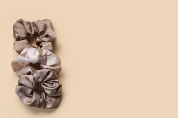 Trendy silk scrunchies on beige background