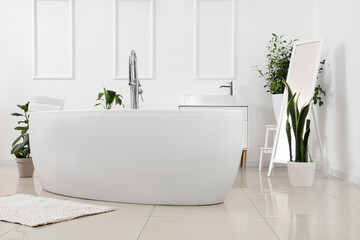 Fototapeta na wymiar Interior of light bathroom with bathtub, sink and plants