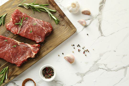 two raw meat on the old wooden cutting board, ready to cook, marble background, top view, copy space