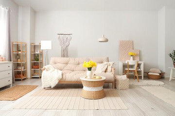 Stylish living room with sofa, coffee table and bouquet of narcissus flowers