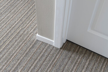 Outside corner baseboard moulding installed in a room with low pile carpet