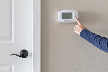 Adjusting programmable thermostat in the room. Lowering room temperature
