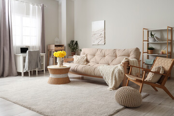 Interior of stylish living room with sofa, bouquet of narcissus flowers and coffee table
