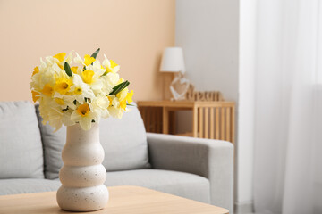 Vase with narcissus flowers on table in living room