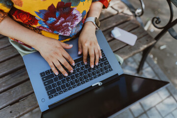 Office outdoors, close-up of female hands typing on a keyboard with a laptop in nature. Nature...