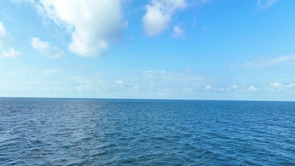 Mesmerizing aerial view captures endless azure sea, gentle waves, and cotton-like clouds against a boundless sky. Drone's-eye serenity. Ocean background.
