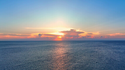 Drone soars over sunset-kissed waves, painting the sky with hues of blue, yellow, and fiery red. Nature's masterpiece from above. Bird's eye view. sea background.
