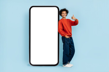 Cheerful man showing thumbs up near phone