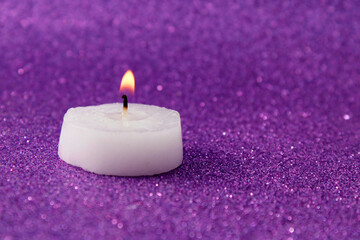 Burning candle on bright purple background