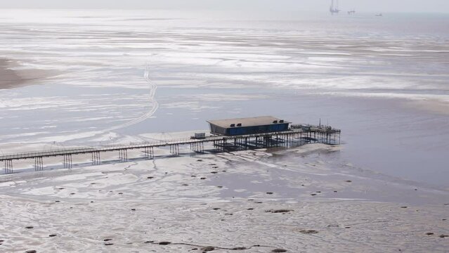 Aerial view looking down at Southport Pier on bright day when the tide is far out