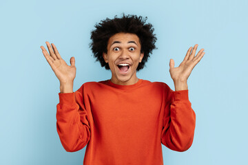 Surprised man with raised hands on blue background