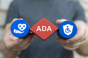 Man holding blocks with icons sees abbreviation: ADA. ADA Americans with Disabilities Act concept. Disability Law Social Services. - obrazy, fototapety, plakaty