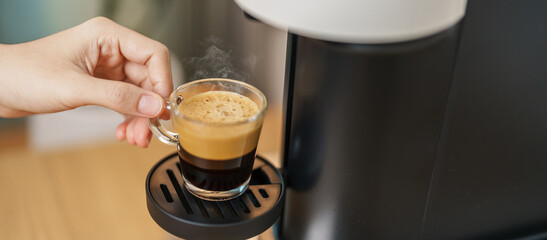 Espresso cup with steam and froth during Coffee making Coffee by Coffee Maker Machine on wood table...