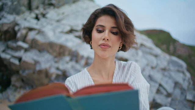 Attractive woman hold book at rocky shore closeup. Focused girl flipping pages