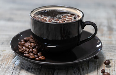 taza negra de cafe con granos al lado 
