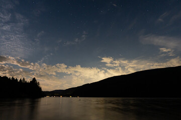 night scene on mountain lake with calm water and cloudy sky
