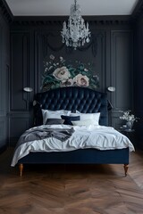 A dark blue velvet bed with a navy headboard, white sheet and pillows in the center of a large room with dark gray walls and a vintage chandelier